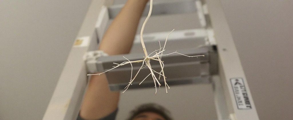 Worker on ladder installing light, unexpected hazard.