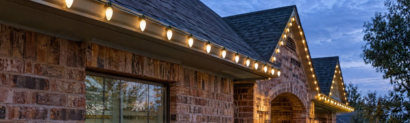 Warm white C9 Christmas bulbs evenly spaced along a brick home's roofline