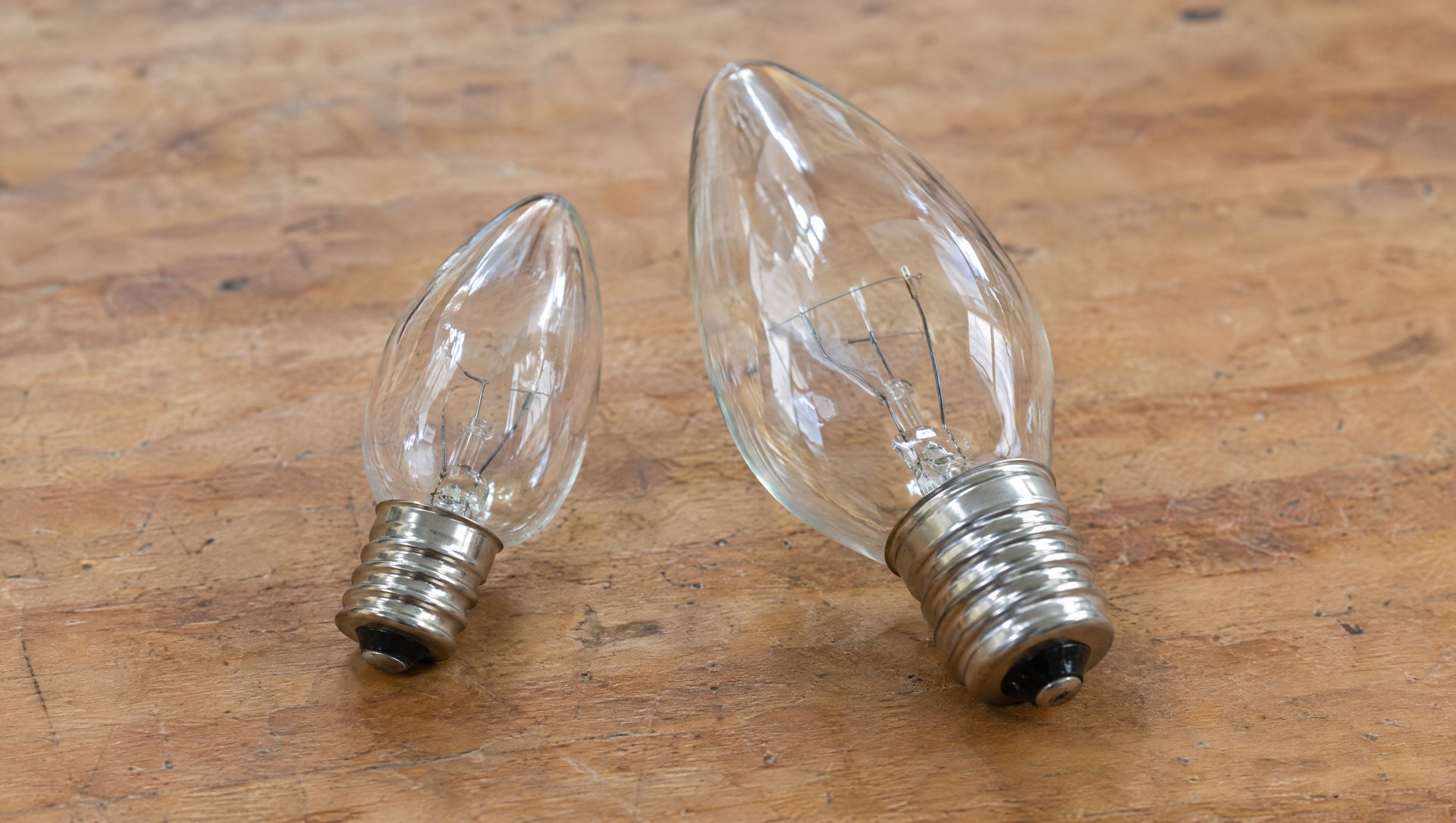 C9 and C7 Christmas light bulbs side by side on a workbench showing bulb and base size