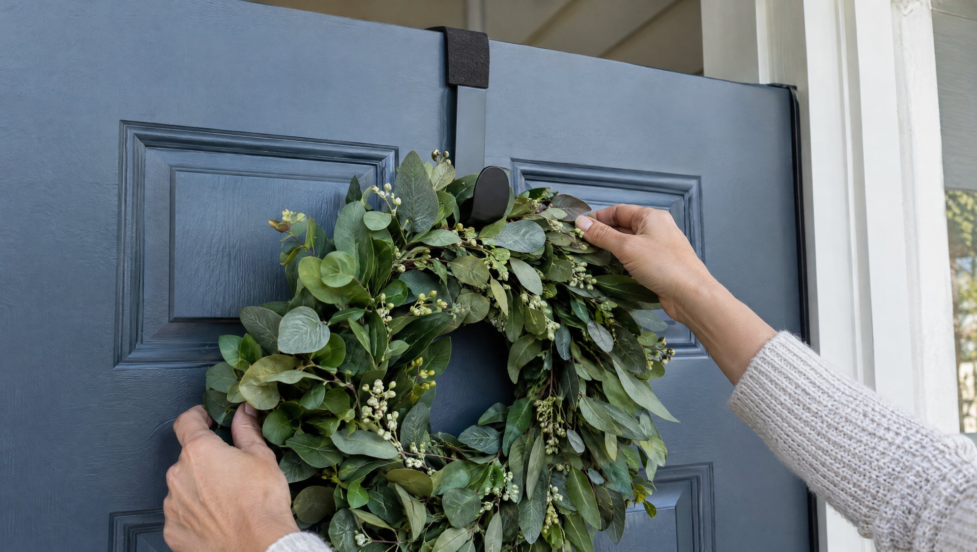 Hands hanging a Christmas wreath on a felt-backed over-the-door hanger