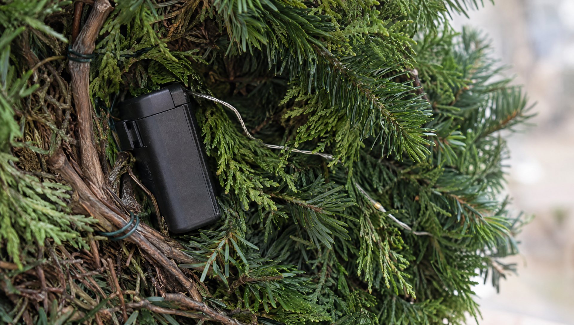 Battery pack tucked behind a lit Christmas wreath, close-up