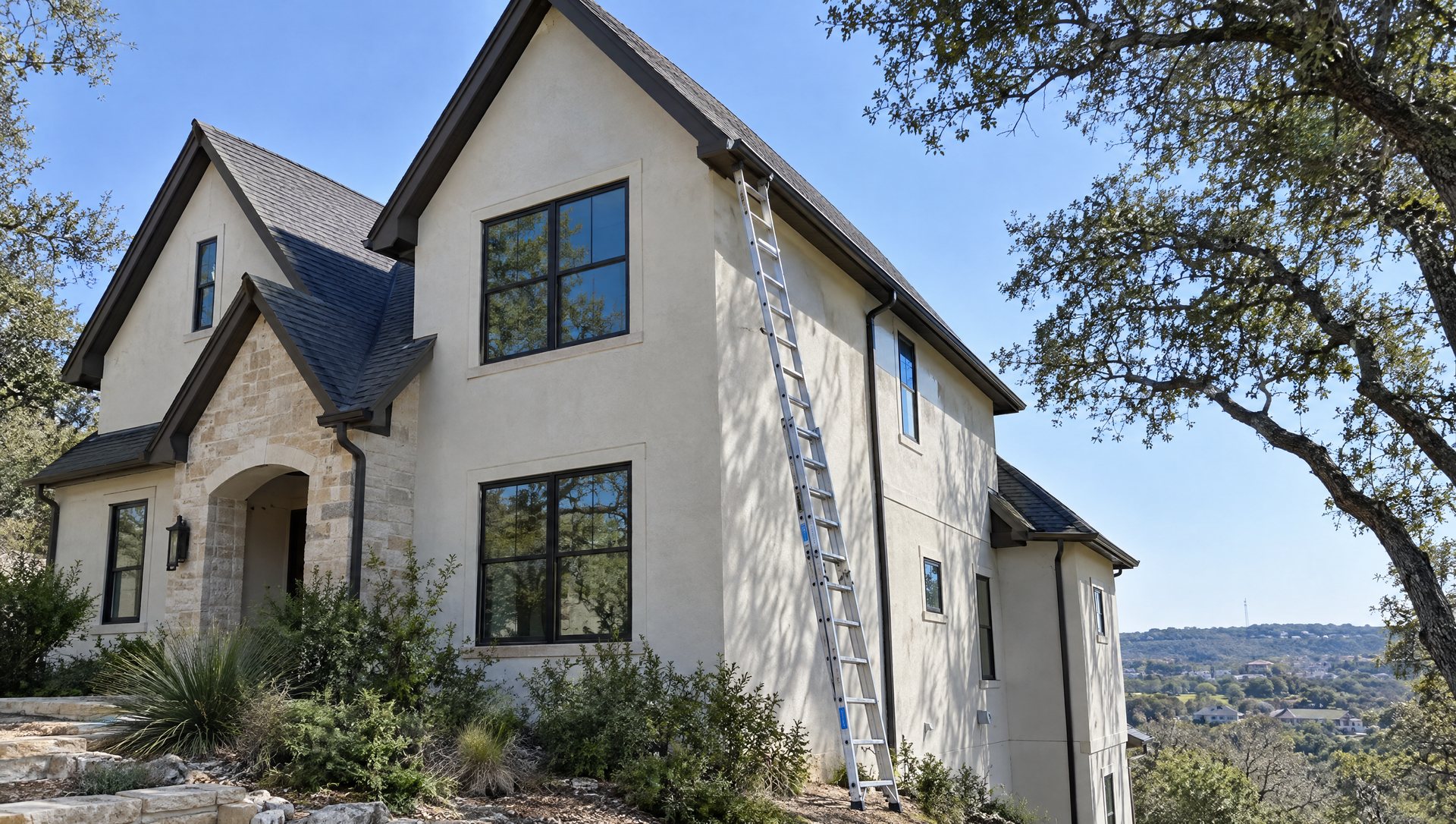 Two-story stucco home with steep gables and an extension ladder reaching the upper eave.