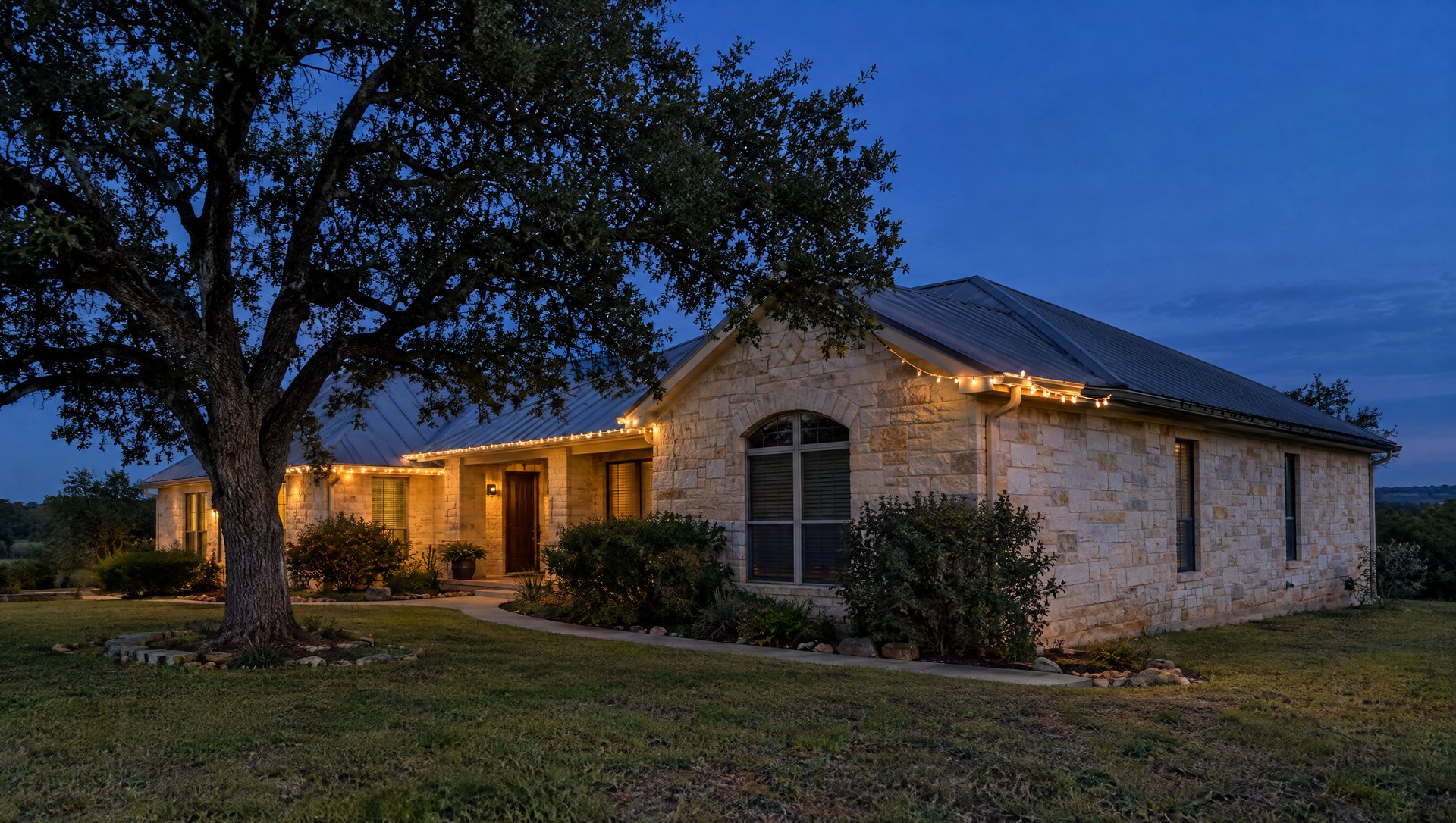 Limestone home at dusk with sagging mini lights on part of the gutter and one dark section.