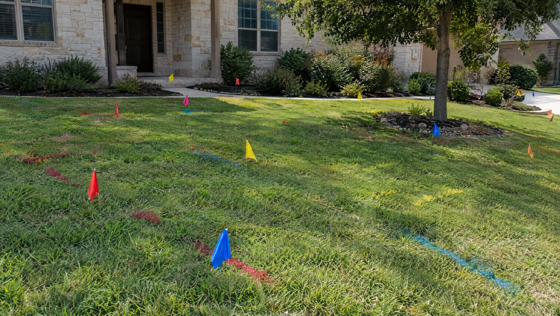 Utility locate flags and paint marks on a front lawn before digging