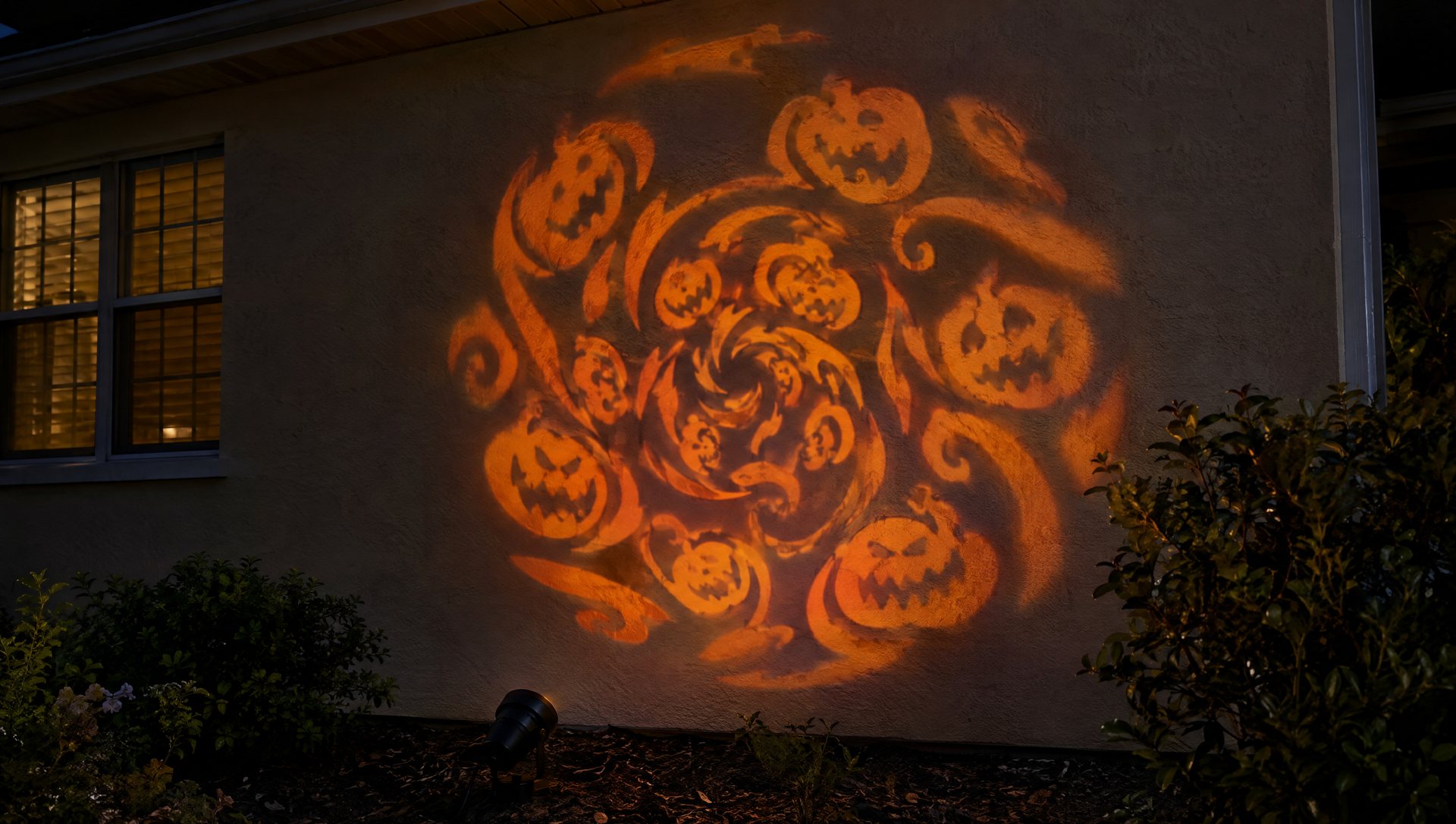 Halloween projector light contained within one plain exterior stucco wall at night