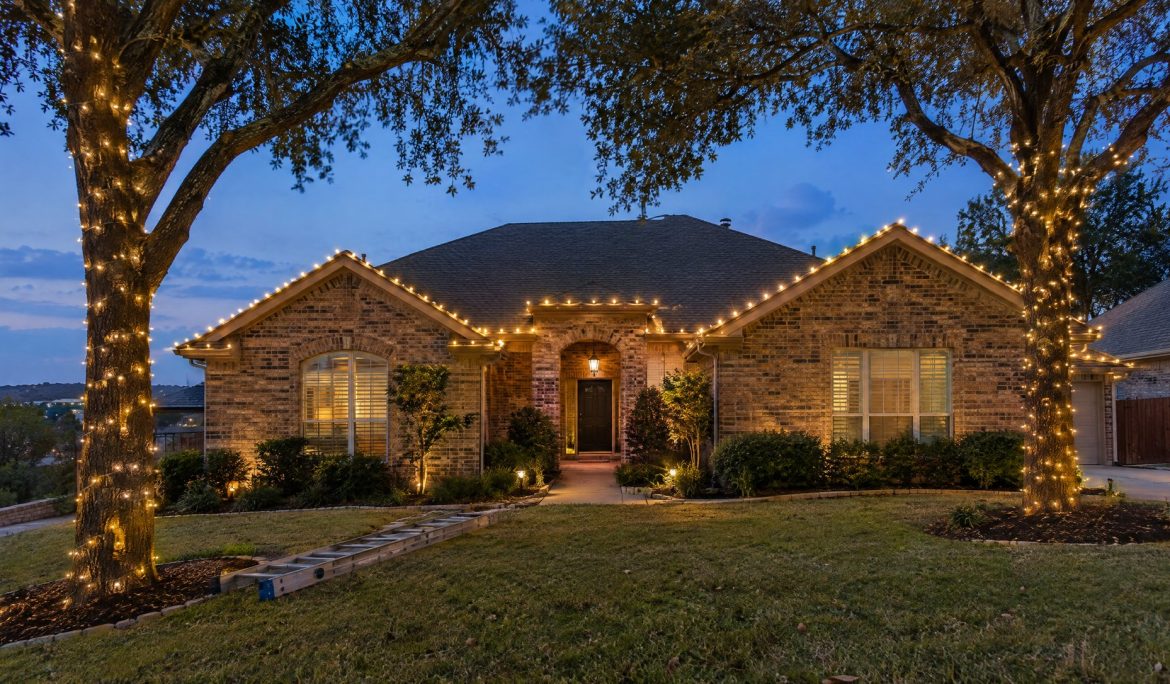 Home at dusk with freshly hung warm white roofline lights and wrapped tree trunks