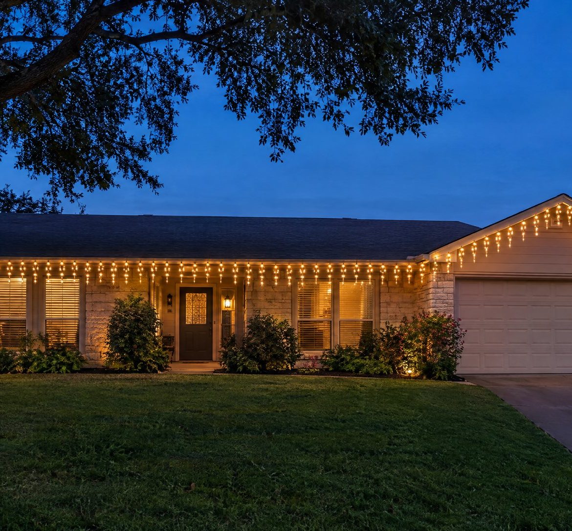 Icicle Lights: How to Hang Them Straight (and When to Skip Them) Evenly hanging warm white icicle lights along a ranch home's eave at night