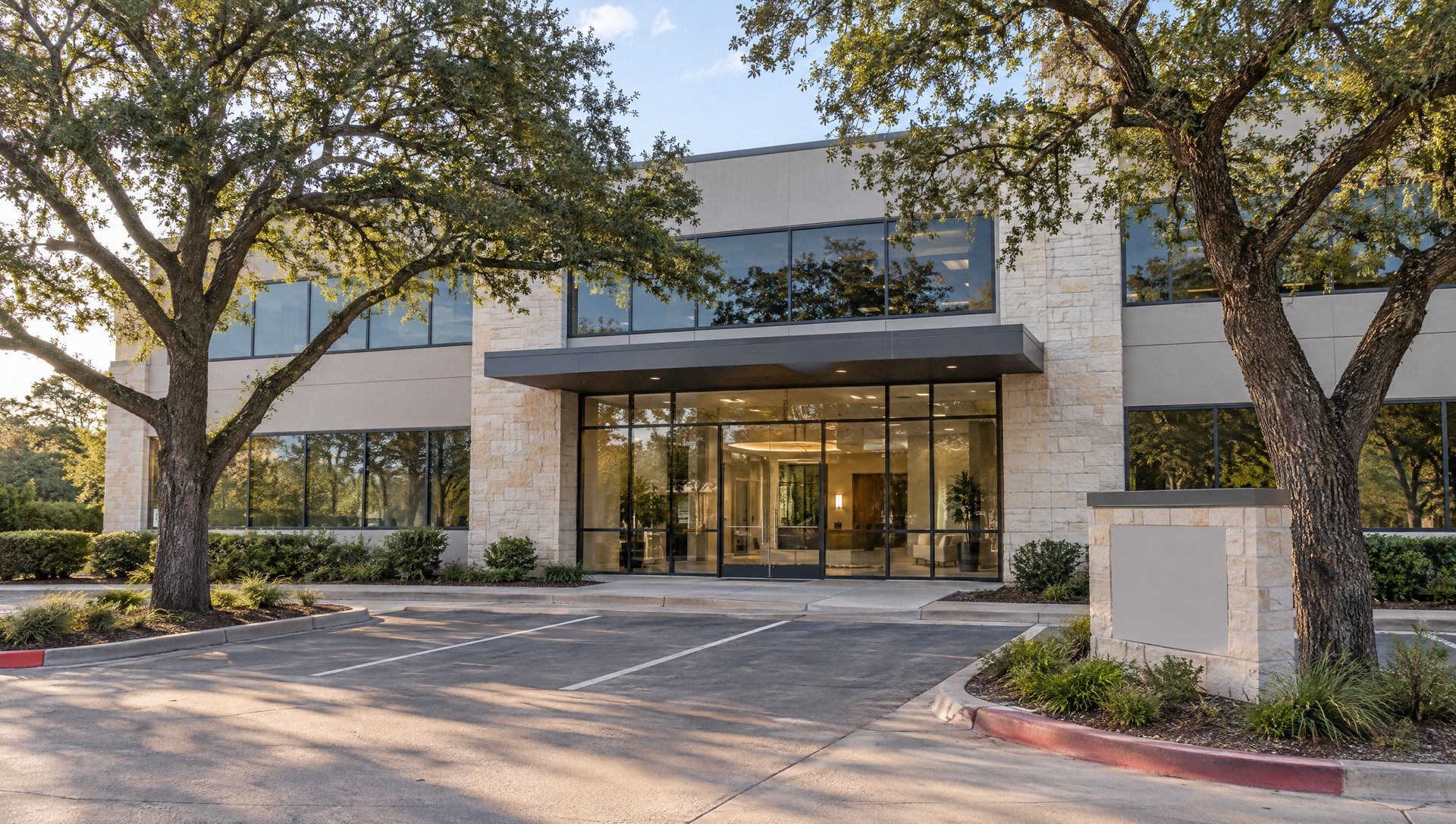 Multi-tenant Austin office building entrance with a canopy and parking-island live oaks before holiday decorating
