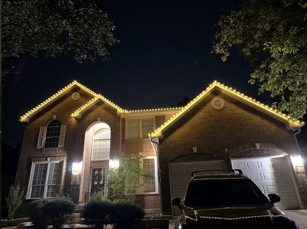 Brick two-story home with warm white roofline lights on every gable