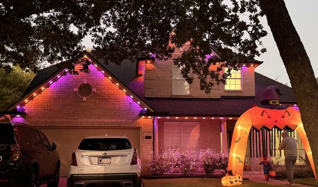 Permanent lights in purple and orange for Halloween, with a pumpkin arch in the yard