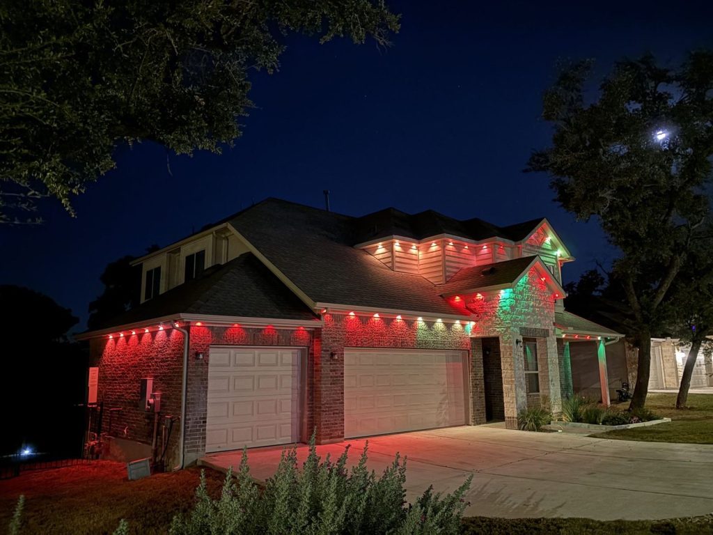 Two-story home with permanent eave lights in red with green accents