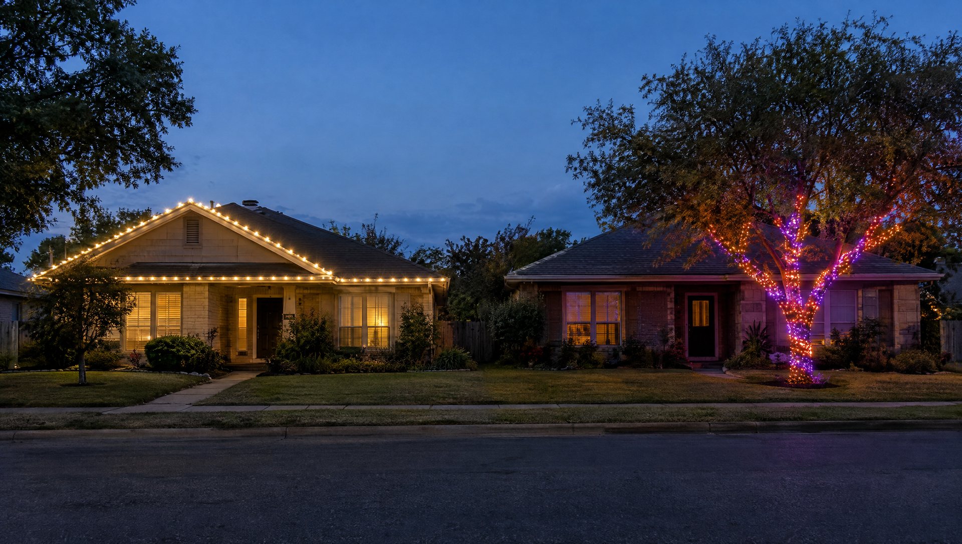 Two Austin homes at blue hour, one with a warm-white roofline and one with a color-changing smart-light tree
